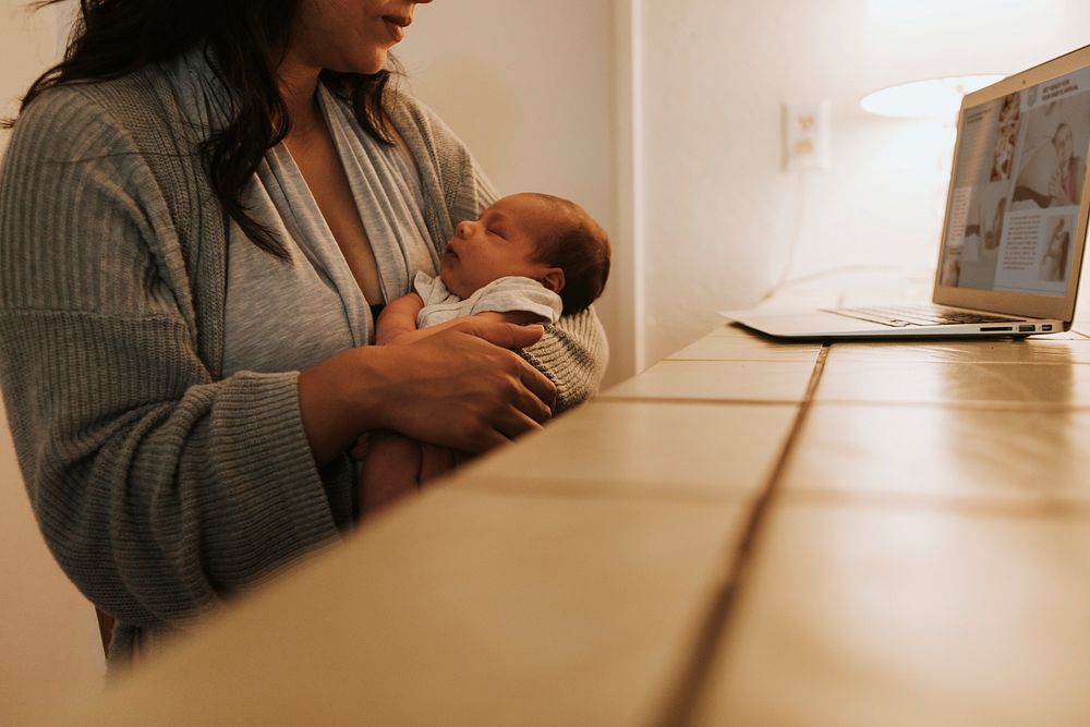 Mother using a computer and holding her baby