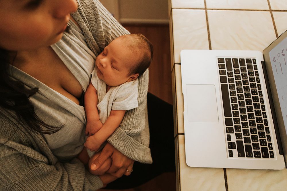 Mother using a computer and holding her baby