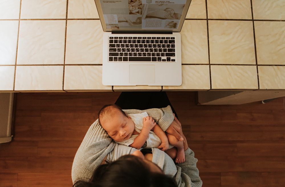 Mother using a computer and holding her baby