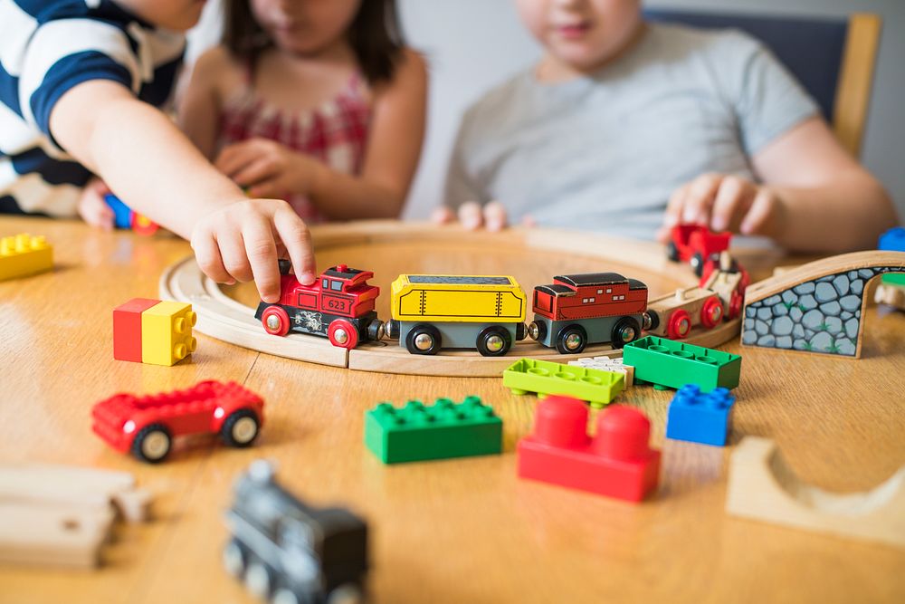 Siblings playing with blocks, trains and cars