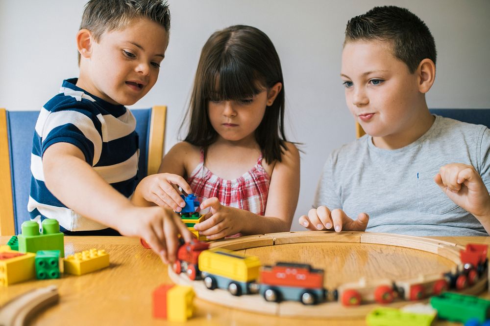Siblings playing with blocks, trains and cars