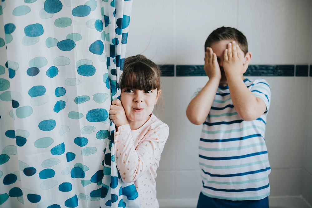 Sister and brother playing peekaboo in the bathroom