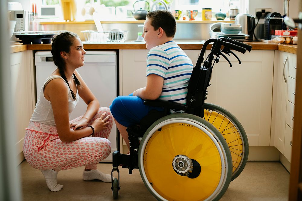 Sister helping her disabled brother in the kitchen