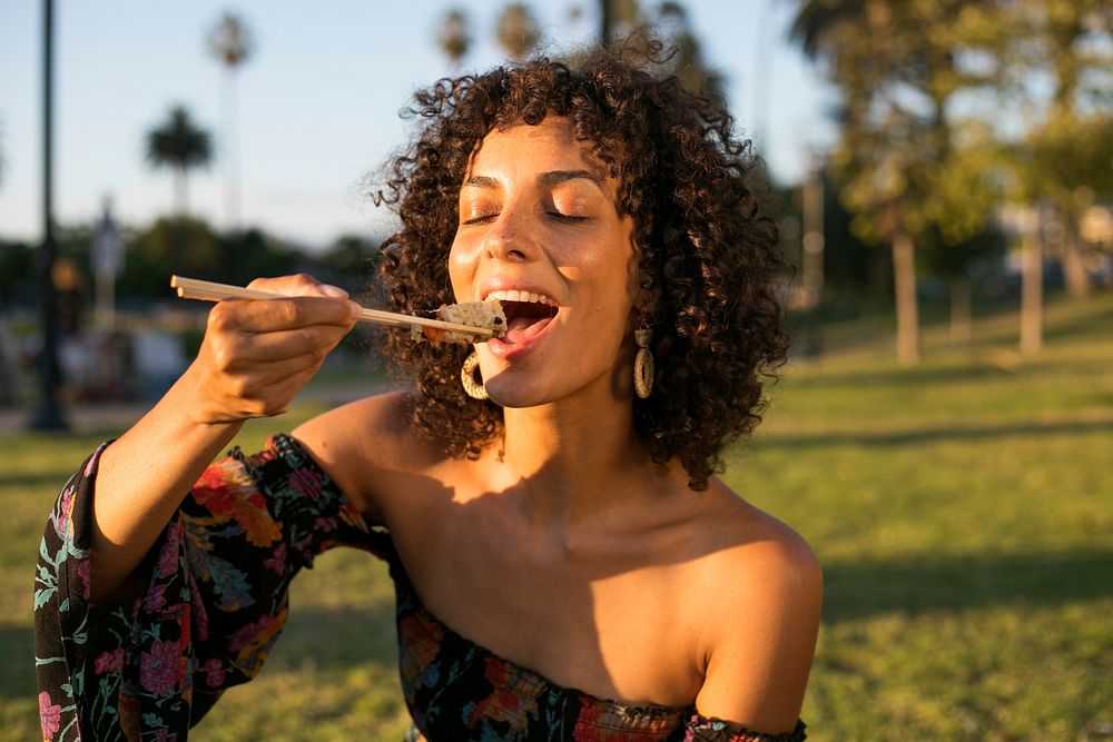 Woman eating sushi in the park