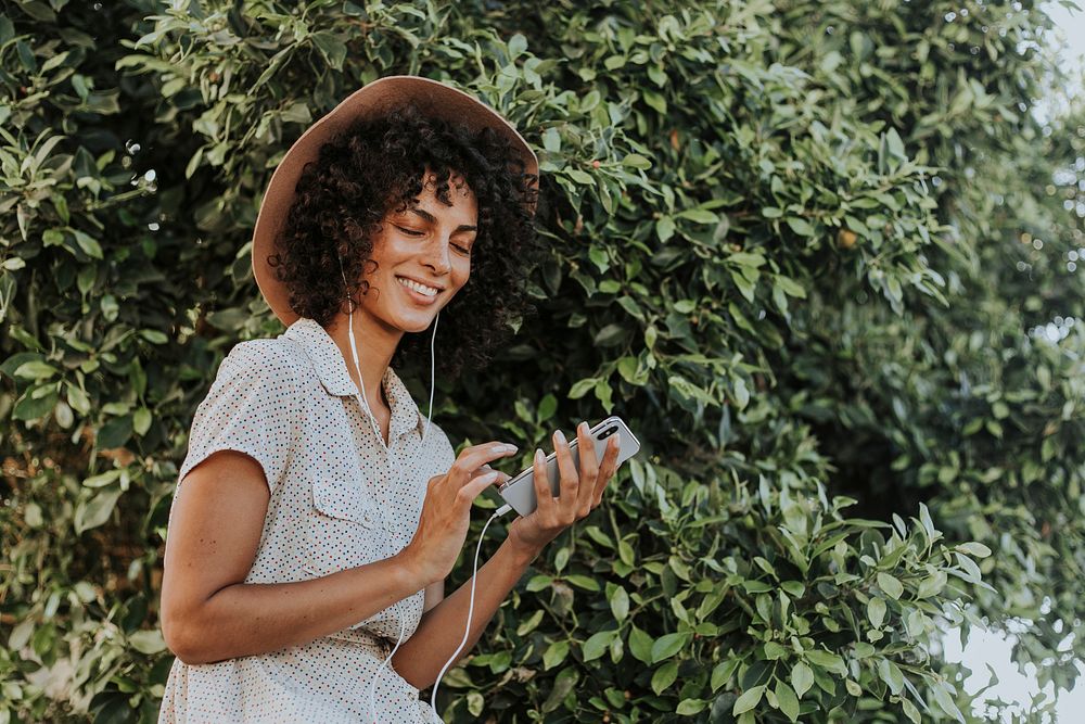 Beautiful woman listening to music in a botanical garden
