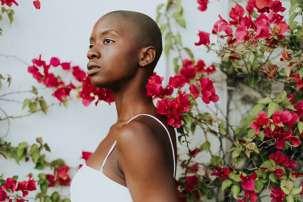 Skinhead woman surrounded by red flowers