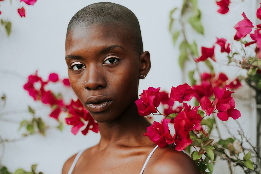 Skinhead woman surrounded by red flowers