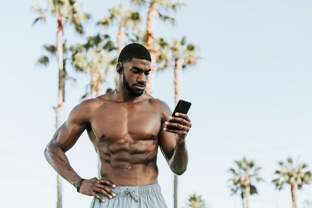Fit man listening to music while at the beach