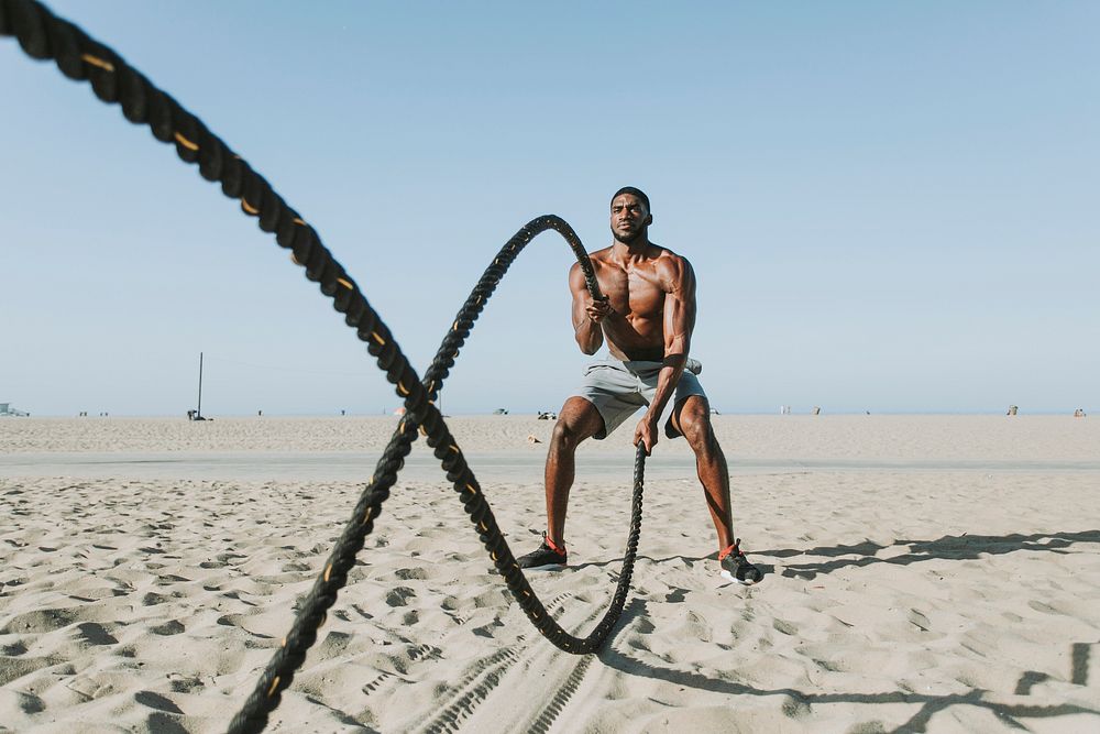 Fit man working out with battle ropes