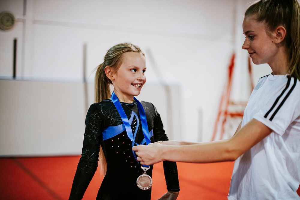 Coach giving a silver medal to a young gymnast
