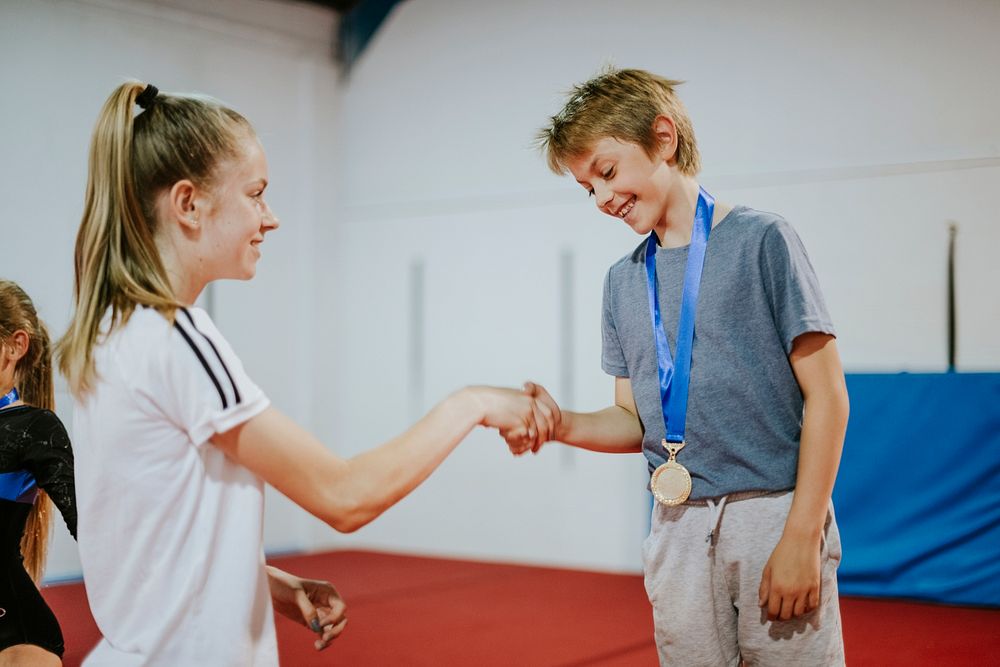 Coach giving a gold medal to a young gymnast