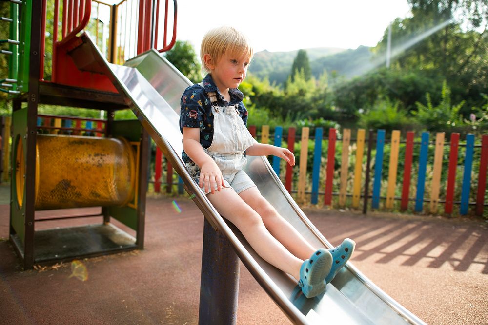 Young boy playing a slide at a playground