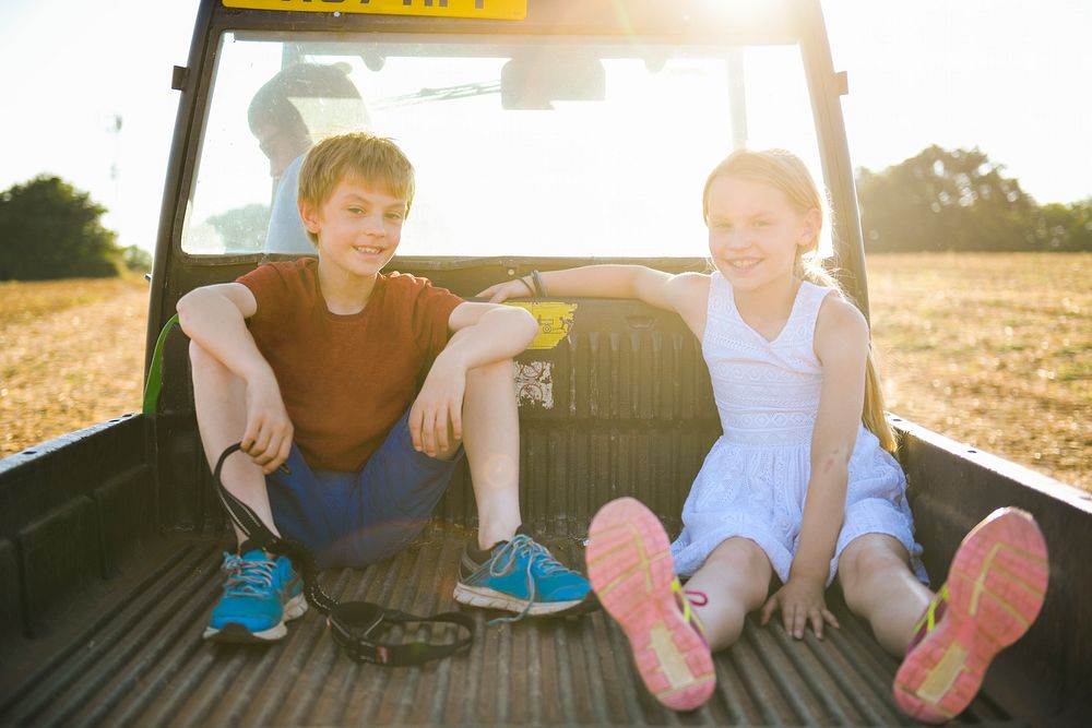 Kids sitting in the back of a truck on a farm