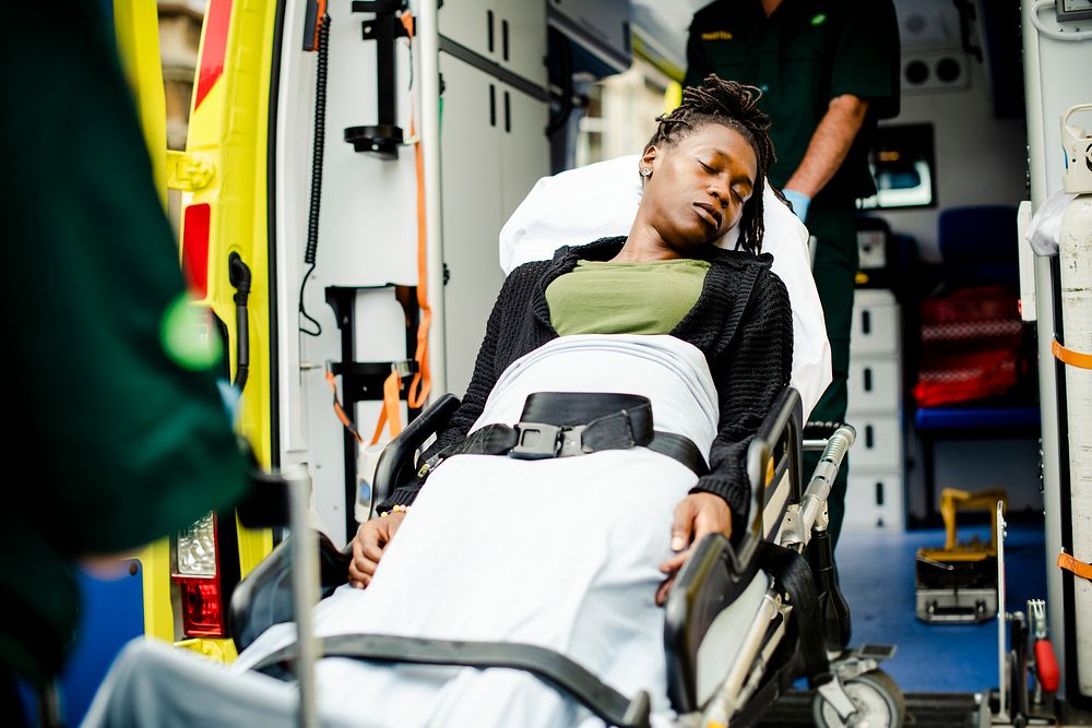 Paramedics moving a patient on a stretcher into an ambulance