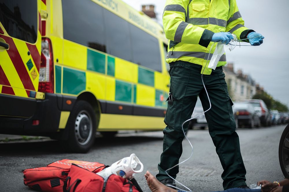 Male paramedic preparing an oxygen mask to an injured woman on a road