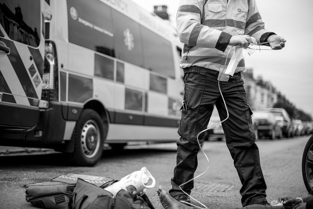 Male paramedic preparing an oxygen mask to an injured woman on a road