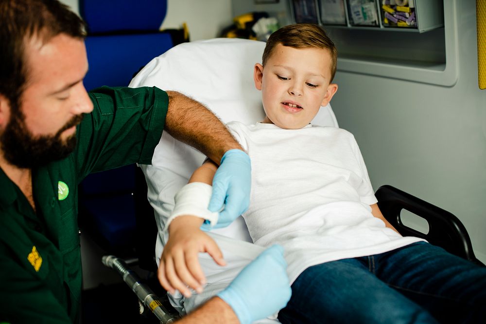 Paramedic giving a first aid to a young boy in an ambulance