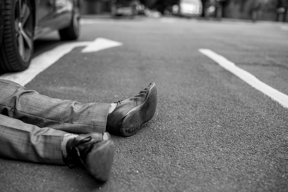 Person lying on the ground after a car accident