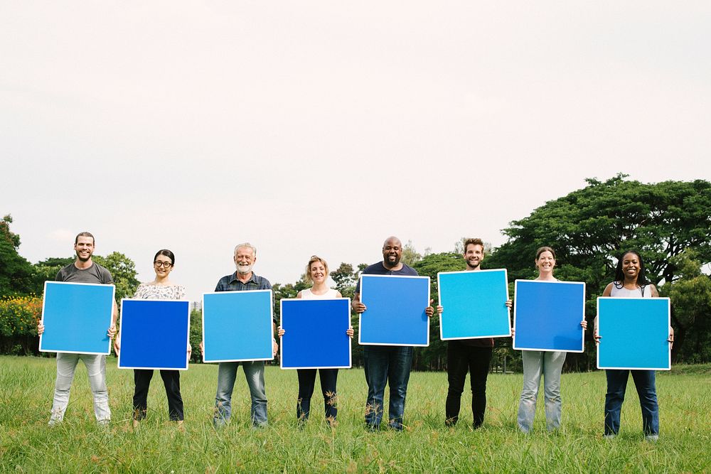 Diverse people holding blue squared boards in the park