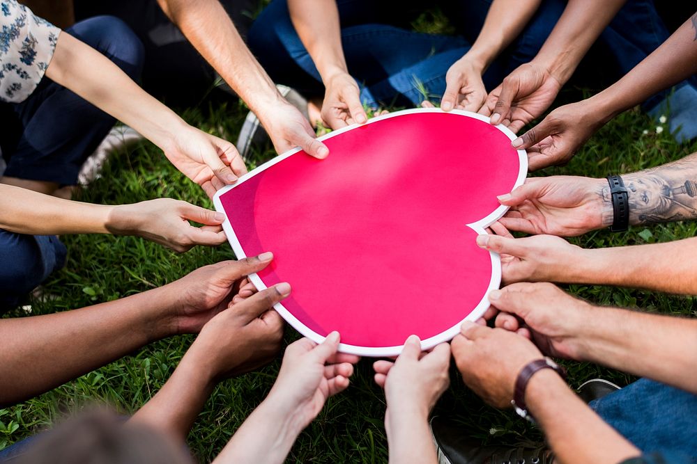 Group of people holding a pink heart icon