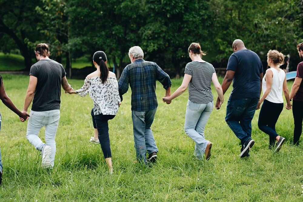 Diverse people holding hands and running in the park