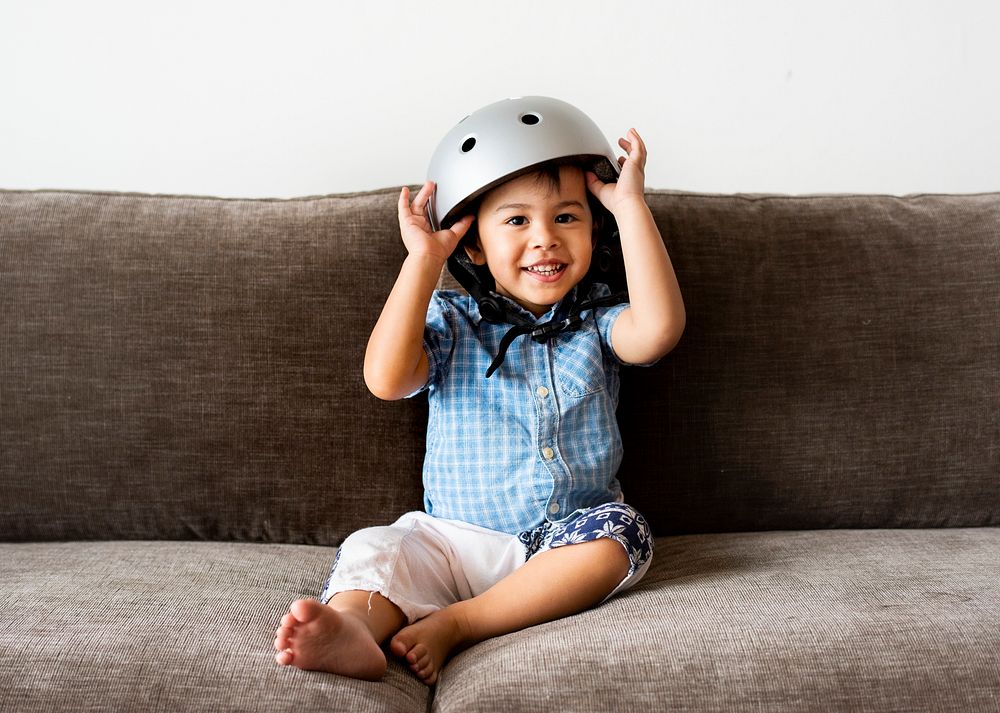 Little boy sitting on a sofa and wearing a helmet