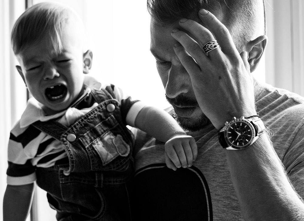 Stressed out father holding a crying baby