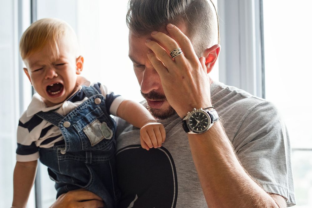 Stressed out father holding a crying baby