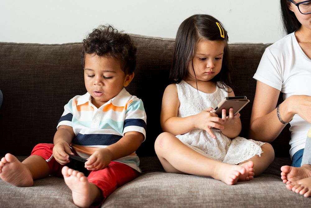 Children on a couch with mom using smartphones