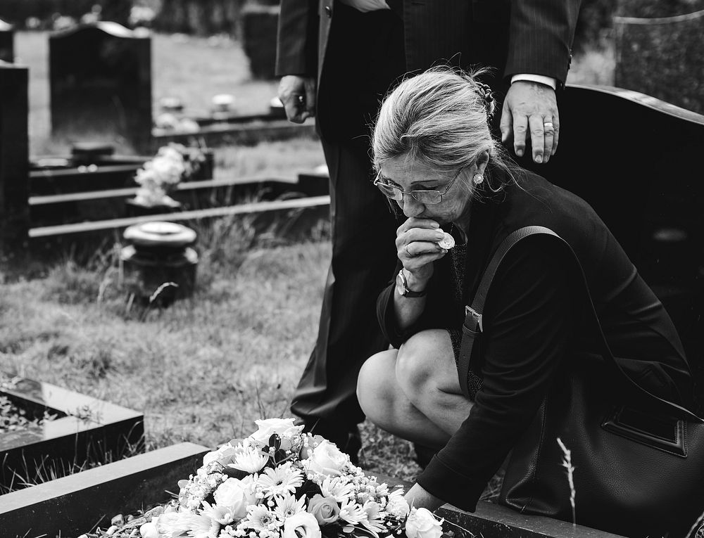 Old woman laying flowers on a grave