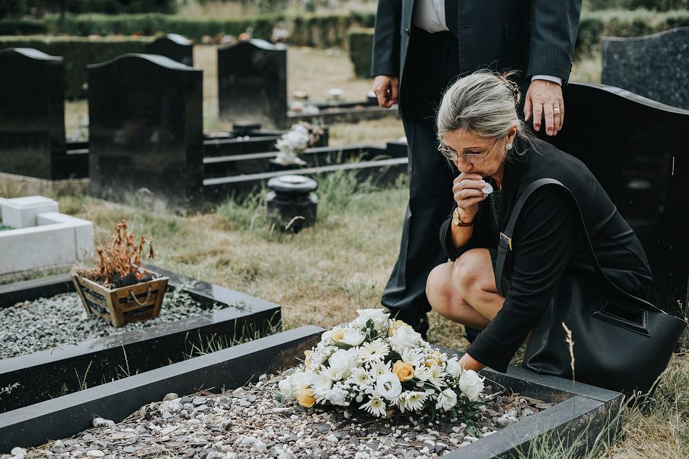 Old woman laying flowers on a grave