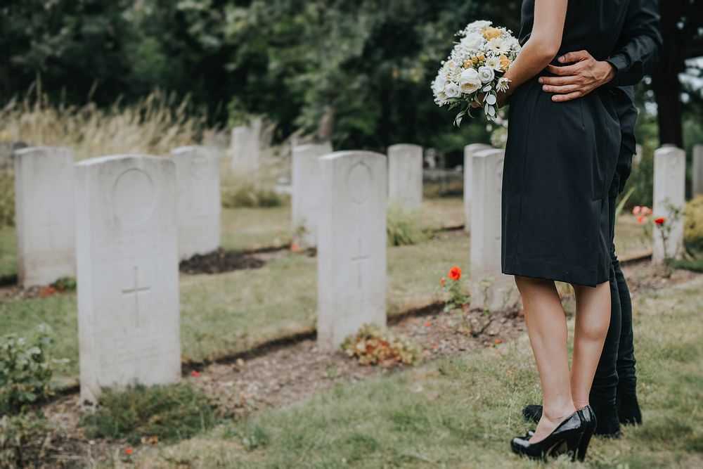 Couple standing together by a gravestone