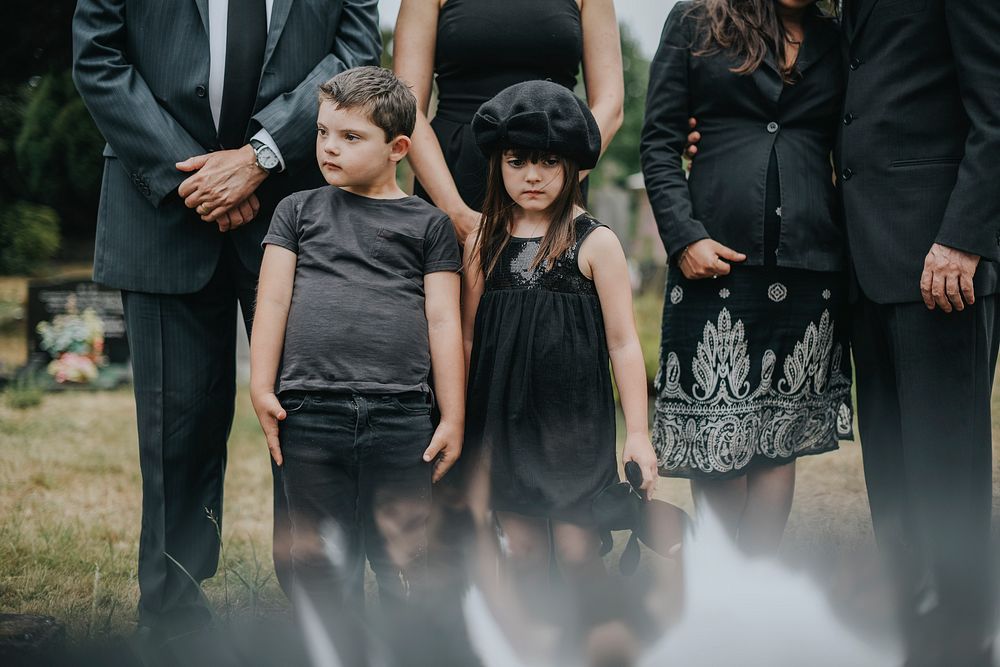 Sad grandkids standing by the grave