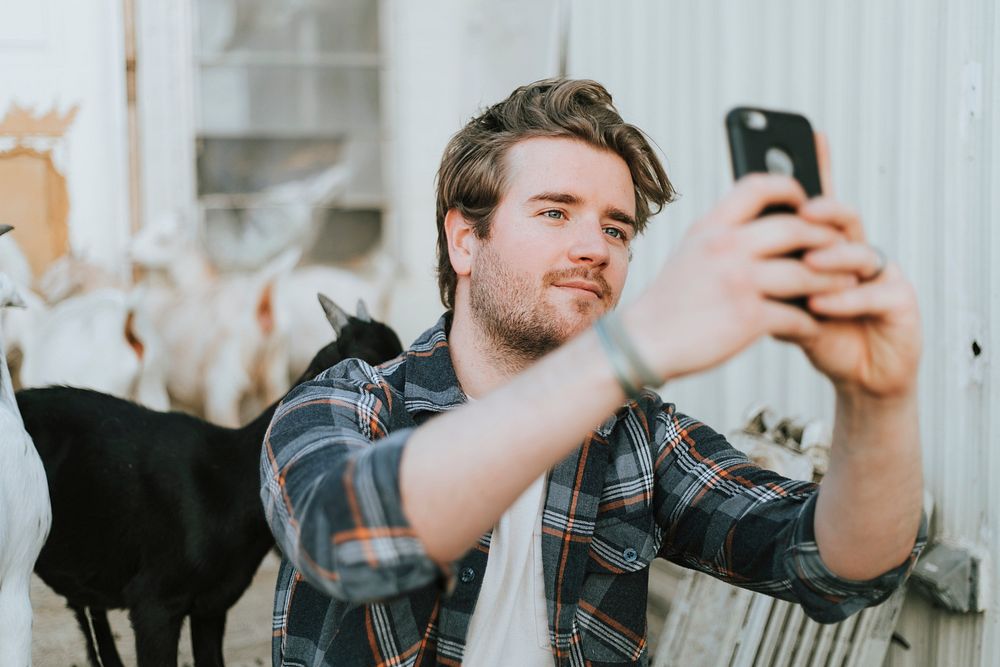Happy man taking a selfie with baby goats