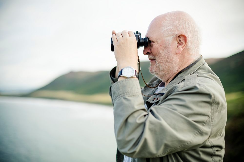 Happy senior man looking through a pair of binoculars