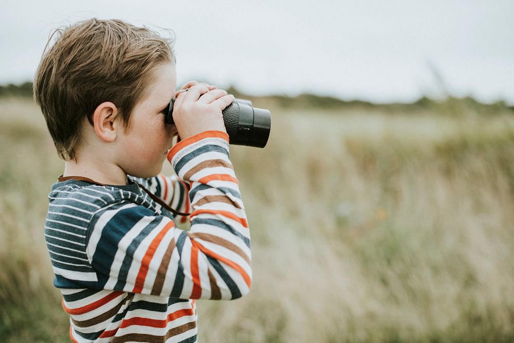 Young boy looking through a pair of binoculars