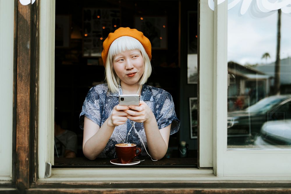 Cool albino girl texting on her phone at a cafe