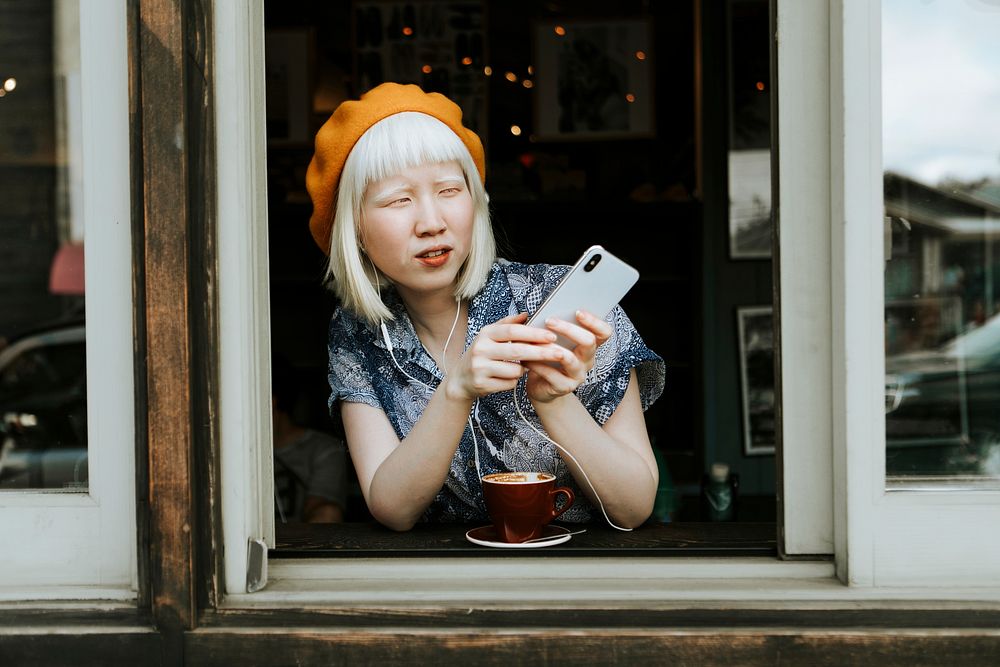 Albino girl with an orange beret sitting at a cafe