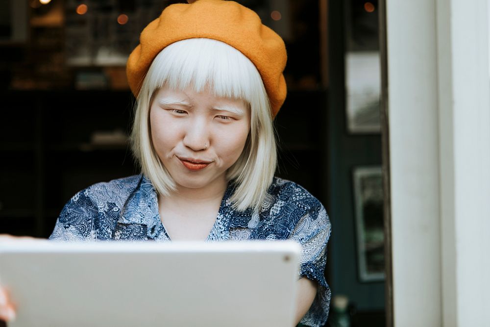 Sweet albino woman using a digital tablet at a cafe