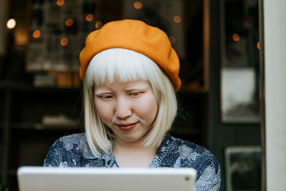 Sweet albino woman using a digital tablet at a cafe