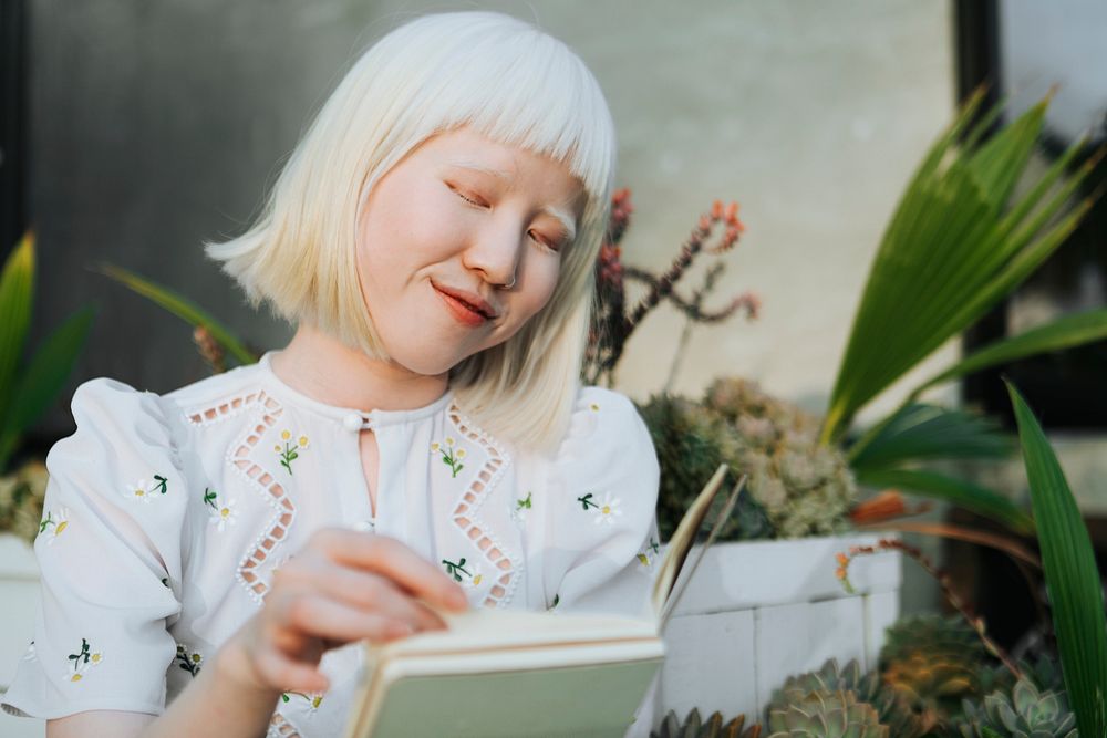Cute albino girl reading a book in her backyard