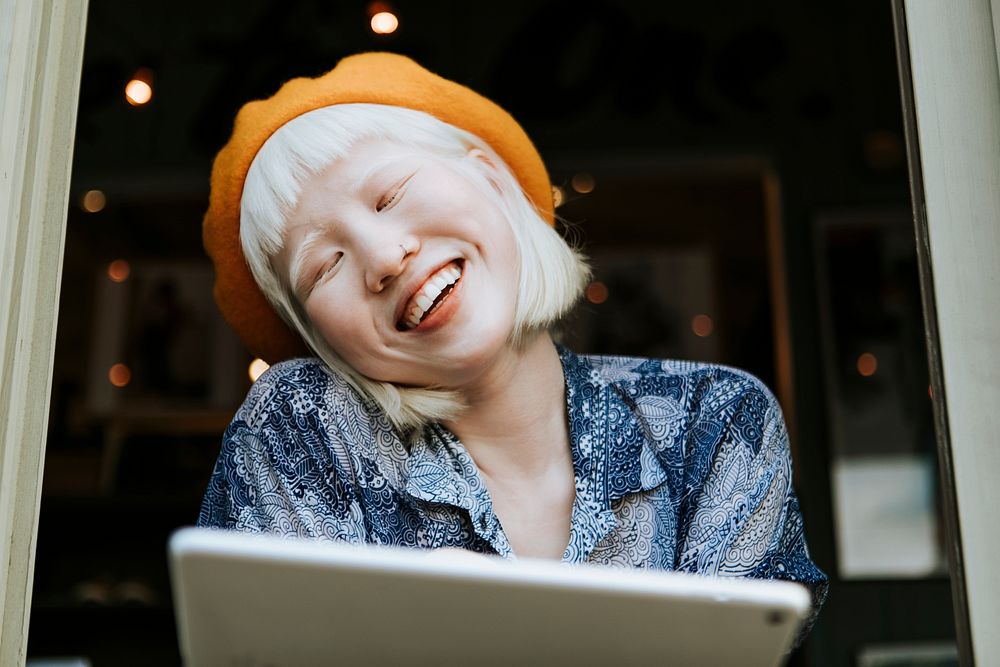 Cool asian albino girl using a tablet at a cafe