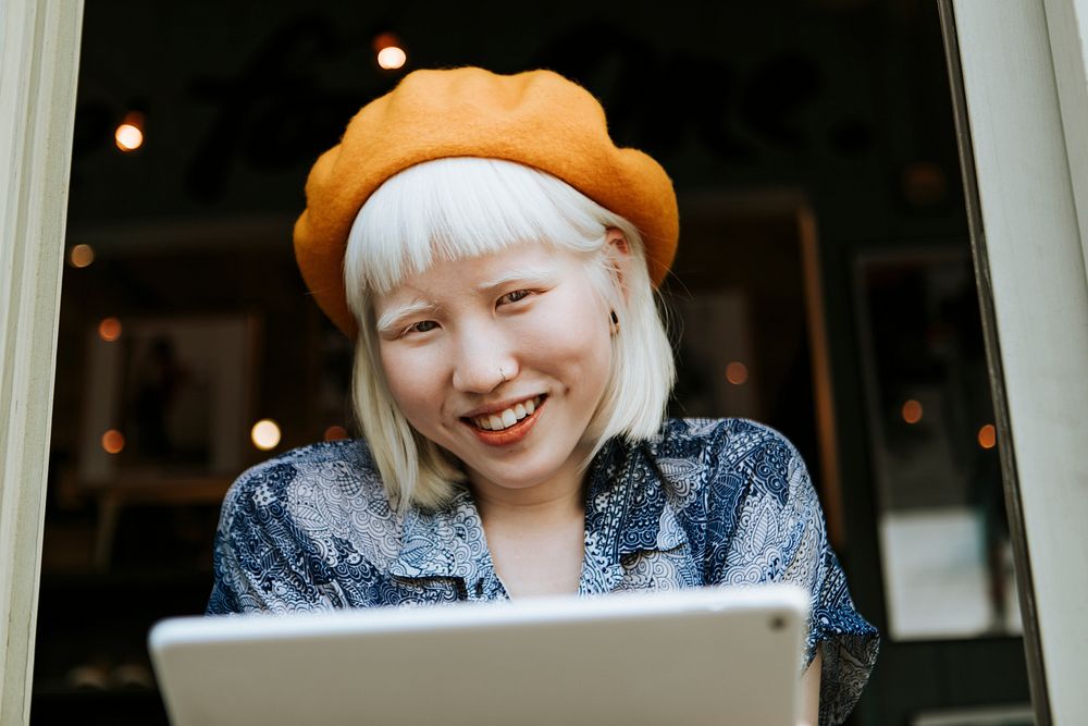 Cool asian albino girl using a tablet at a cafe