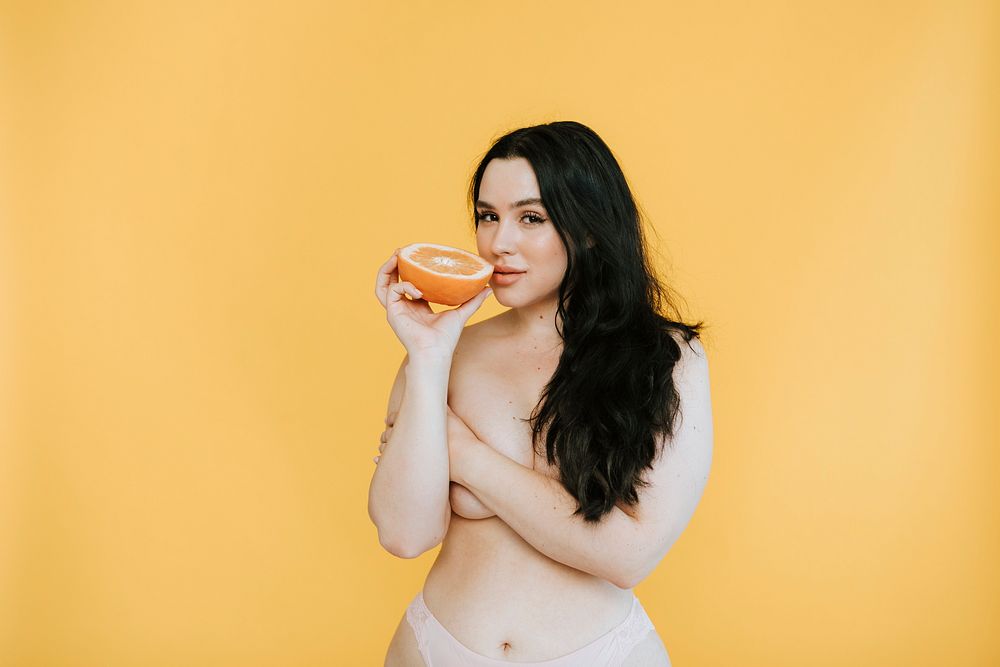 Partially nude woman holding a fresh orange