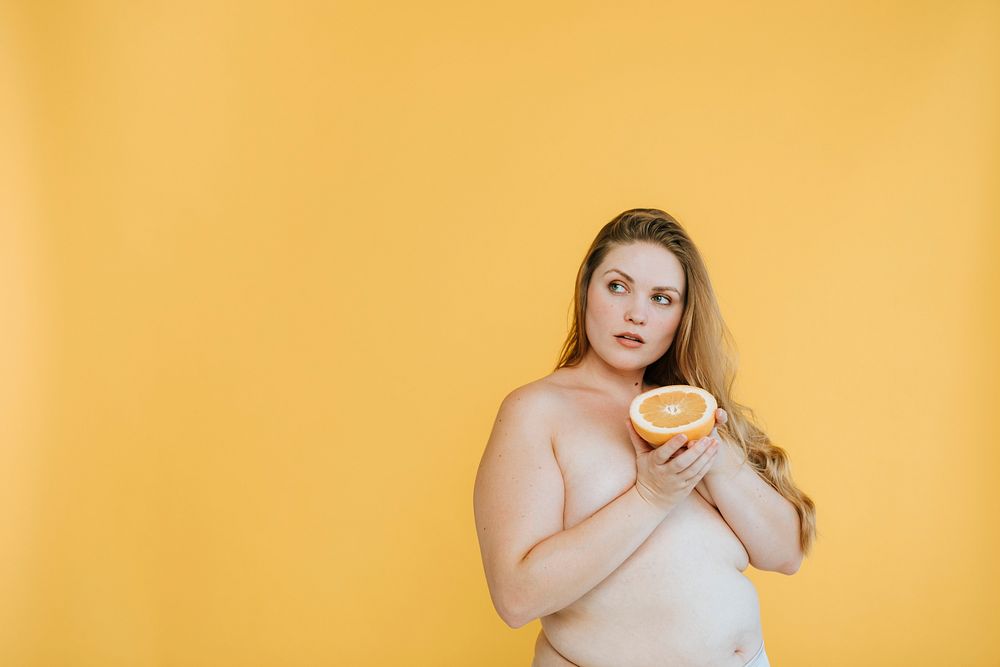 Plus size partially nude woman holding an orange