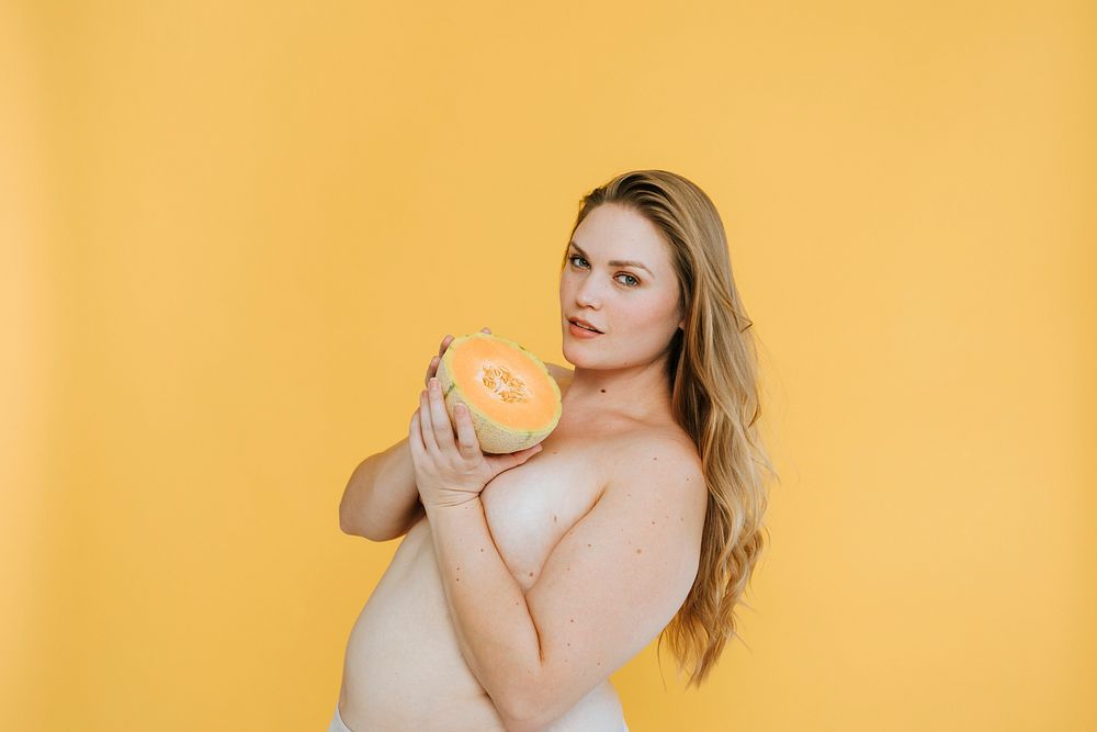 Confident partialy nude plus size woman holding a cantaloupe