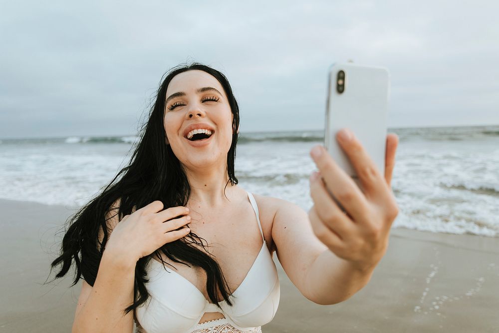 Cheerful plus size woman taking a selfie at the beach