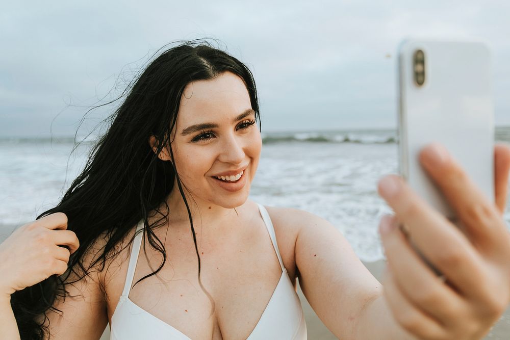 Cheerful plus size woman taking a selfie at the beach