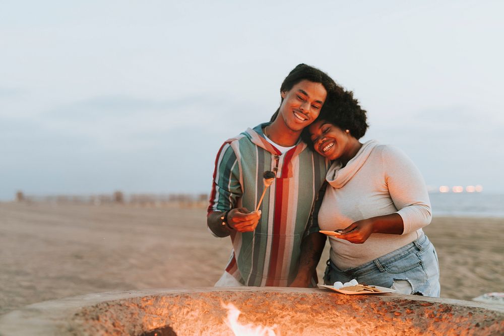 Couple making s'mores at the beach