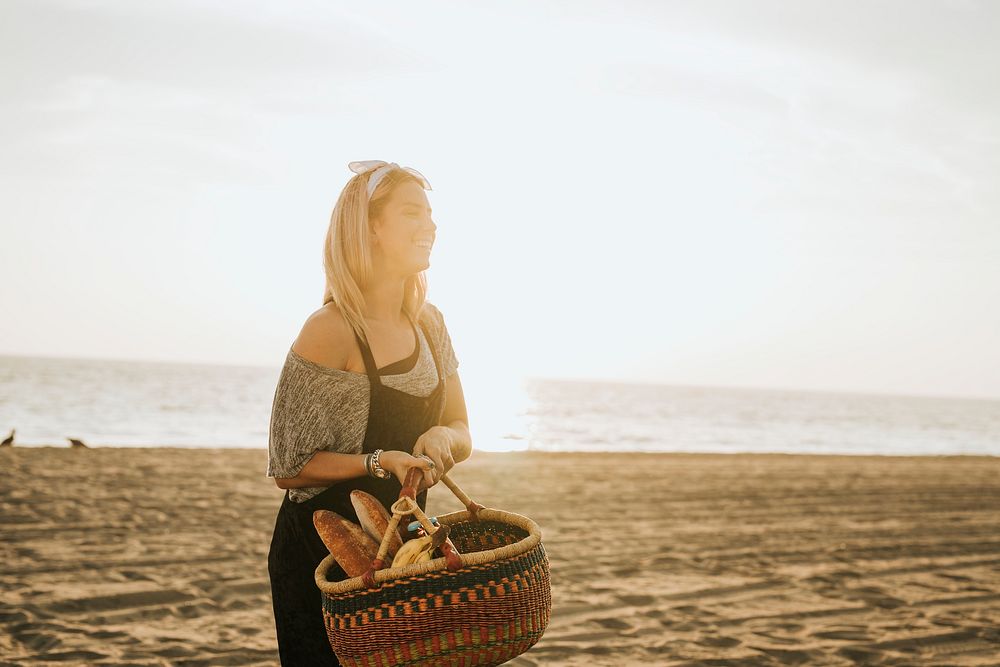 Woman waking with a picnic basket at the beach